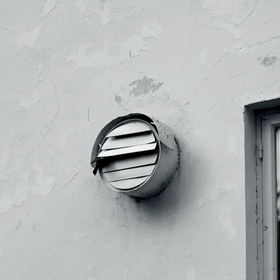 Grilă rotundă de evacuare pe peretele exterior al unui apartament
